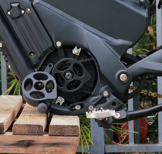 A black plastic motor cover for a Talaria XXX electric bike, installed and mounted on the bike's motor area, with visible bolts and mounting hardware.