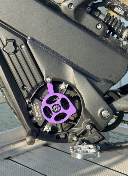 A purple motor cover for a Talaria x3 electric bike emoto, mounted and installed on the bike's motor area, with visible bolts and mounting hardware.